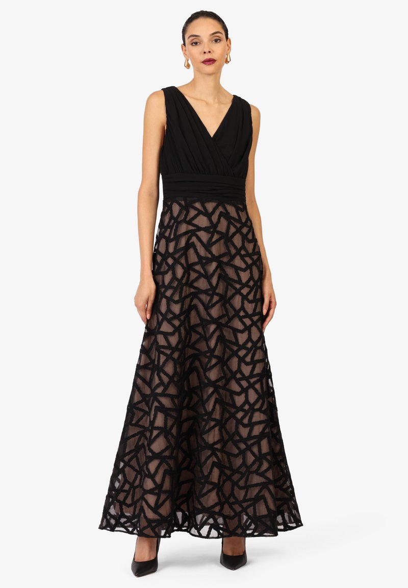 Schwarzes Abendkleid mit V-Ausschnitt, kurzen Ärmeln und figurbetontem Oberteil. Der Rock ist halbtransparent mit einem geometrischen Spitzenmuster.