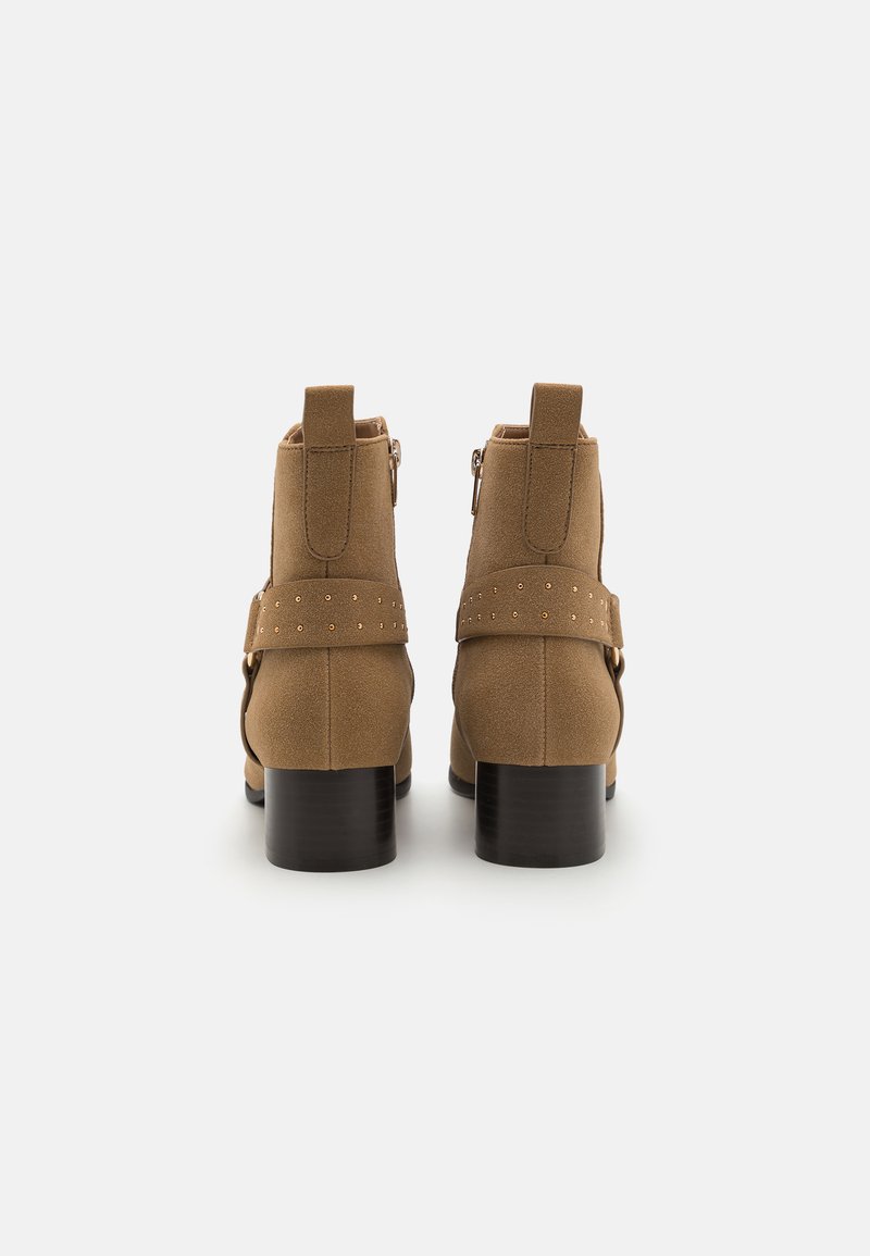 Botines de ante marrón con un acabado suave, cremallera trasera, cinta decorativa con tachuelas y un tacón negro en bloque.