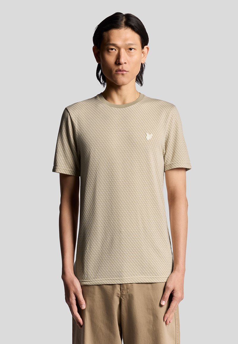 Kurzarm, hellbeige T-Shirt mit strukturiertem Muster; runder Ausschnitt; verfügt über ein kleines, dezentes Logo auf der Brust.