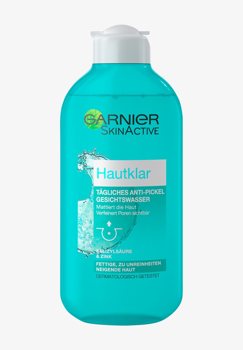 Blauwe plastic fles met een flip-top dop. Het etiket bevat vetgedrukt zwart-wit tekst die een anti-vlekkente gezichtsreiniger met salicylzuur en zink beschrijft.