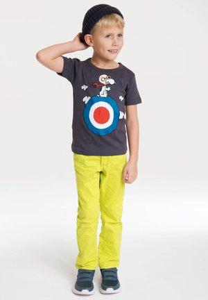Gray t-shirt with a Snoopy graphic, blue and red target design; paired with bright yellow pants and black slip-on shoes.