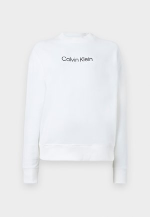 Baltas džemperis, pagamintas iš minkštos medžiagos, su apvalia iškirpte ir ilgomis rankovėmis. Priekyje yra juodas "Calvin Klein" logotipas.