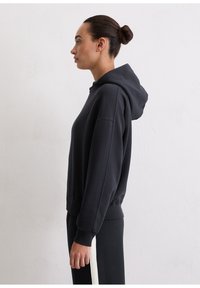 Zwarte hoodie met capuchon en een comfortabele pasvorm, geribbelde manchetten en zoom, gemaakt van zachte stof, weergegeven op een neutrale achtergrond.