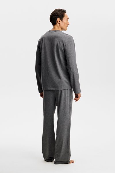 Szürke pamut otthoni ruha szett, amely hosszú ujjú felsőből és hozzáillő, laza fazonú nadrágból áll, mindkettő sima textúrájú és egyszerű kialakítású.