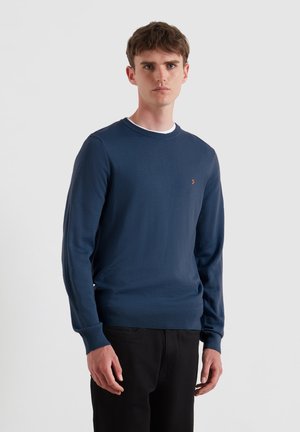 Maglione lavorato a maglia blu navy con maniche lunghe, scollatura rotonda e polsini a coste. Presenta un piccolo logo sul lato sinistro del petto.