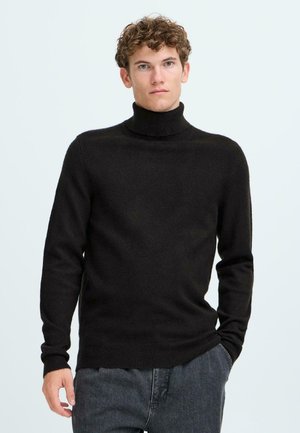 Schwarzer Rollkragenpullover mit weicher Textur und tailliertem Design. Hat lange Ärmel und ein geripptes Halsbündchen, kombiniert mit dunklen Jeans.