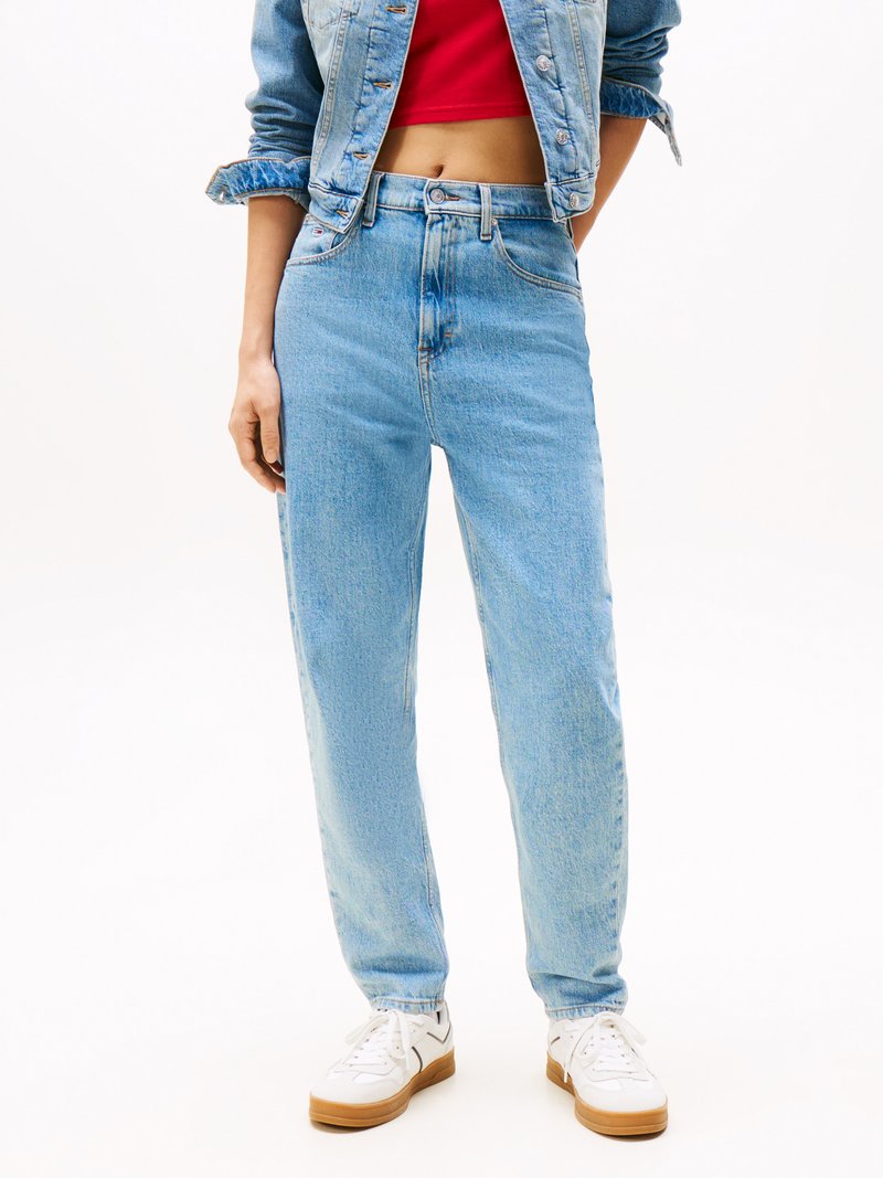 Jeans din denim de culoare albastru deschis cu un croi drept, talie înaltă și decolorare subtilă; asortați cu adidași albi și un top scurt roșu.