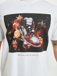 Tricou alb din bumbac, cu un print grafic ce reprezintă teniși roșii înconjurați de flori colorate și textul "RENASSIRSSANCE" dedesubt.