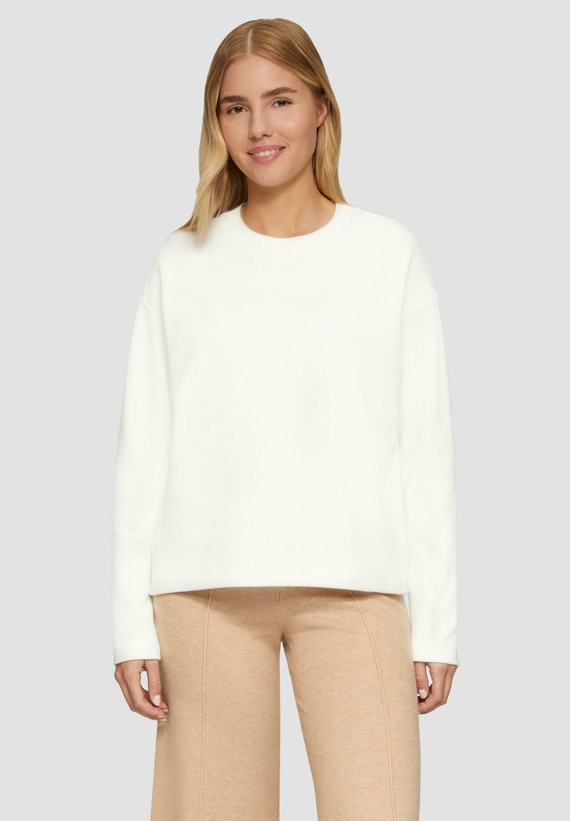 Witte sweatshirt met ronde hals, lange mouwen en een relaxed fit. Gemaakt van zachte stof, gecombineerd met lichtbeige broeken.