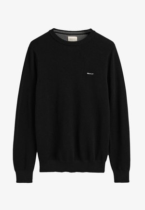 Suéter negro de punto con mangas largas, cuello redondo, puños y dobladillo acanalados, que presenta un pequeño logo blanco en el pecho.