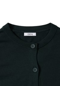 Schwarze Strickjacke mit geripptem Rundhalsausschnitt, zwei schwarzen Knöpfen mit eingeprägtem "CECIL" und einem weißen Etikett mit "CECIL"-Aufschrift.