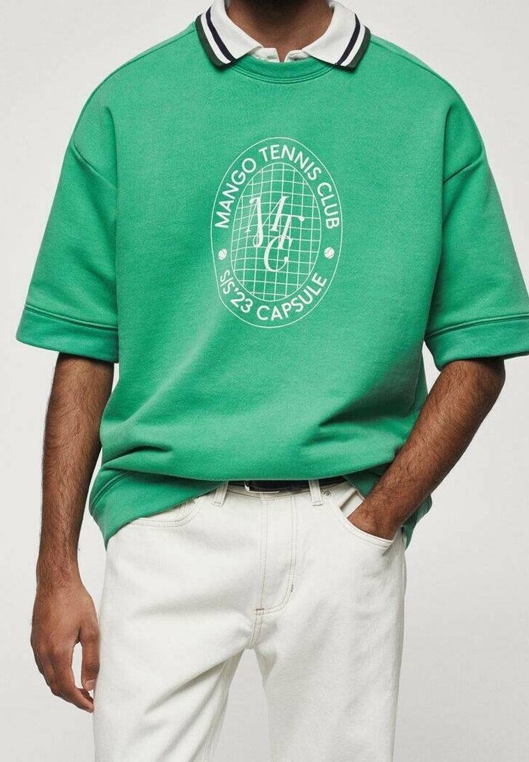 Zelený oversized polo svetr s bílou grafickou logem "MANGO TENNIS CLUB" a černobílým límcem, spárovaný s bílými kalhotami.