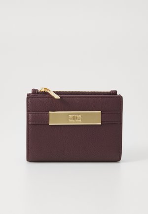 Burgundy leather wallet with a textured finish, gold hardware, and a front logo plate. Compact design with a zip closure on top.
