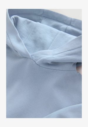 Jasnoniebieska bluza z kapturem o miękkiej teksturze, z zaokrąglonym kapturem i widocznymi detalami szwów, prezentująca prosty i funkcjonalny design.