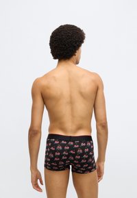 Fekete boxeralsó cseresznye mintával és piros részletekkel, testhez simuló szabással és puha anyagból, hátulnézetben.