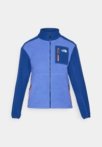 Niebieska i fioletowa polarowa kurtka z wysokim kołnierzem, zapinana na zamek z przodu, z kontrastową pomarańczową kieszenią na klatce piersiowej. Posiada boczne kieszenie na zamek.