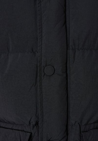 Schwarze Pufferjacke mit gestepptem Design, ausgestattet mit einem runden Knopfverschluss und sichtbaren Nähten. Glattes, leichtes Material.