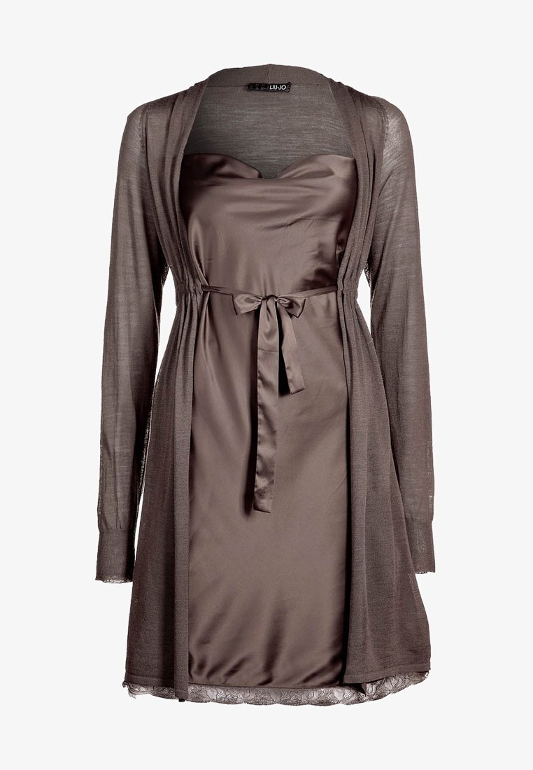 Robe marron avec un corsage en satin et une superposition transparente à manches longues. Présente un nœud à la taille et une bordure en dentelle à l'ourlet.
