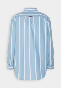 Camisa de manga larga azul claro con rayas verticales blancas, cuello abotonado y detalle de canesú en la parte trasera. Tela de algodón con un ajuste relajado.