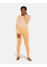 Long-sleeve, light orange top with fitted design, paired with matching leggings. Soft texture with subtle color gradient and seam detailing.