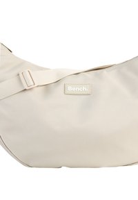 Beige Nylon Schultertasche mit glatter Oberfläche, verstellbarem Tragegurt und rechteckigem Logopatch mit dem Wort "Bench." in einer dezenten Schriftart.