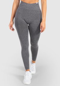 Hoge taille grijze leggings van rekbaar materiaal, met een gladde textuur en een fitted silhoutte, gecombineerd met witte sneakers.