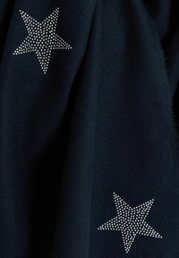 Tissu bleu marine avec deux motifs d'étoiles argentées composées de petits strass, créant un détail texturé et réfléchissant sur le matériau.