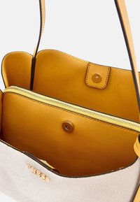 Vászontáska világosszürke textil külsővel és két mustárbőr rekesszel. Réz patentszárral és arany zippzáros zsebből áll.
