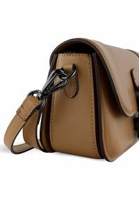 Bolso de piel marrón con un diseño estructurado, que presenta un borde oscuro en contraste, un clip metálico y una correa ajustable y delgada.