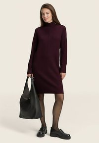 Burgundia pika varrukaga kleit kõrge kaelusega, soonilise tekstuuriga ja keha järgiva lõikega. Ühildatud musta käekoti ja massiivsete kingadega.