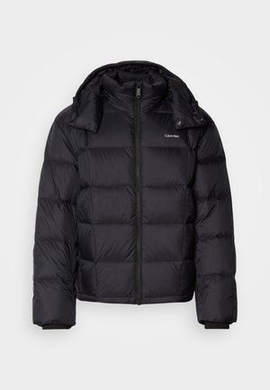 Melna pūkaina jaka ar rāvējslēdzēju priekšā, īsā garumā, ar quilted dizainu un augstu apkakli. Iespējas ietver logo uz kreisās krūtis un elastīgas aproces.