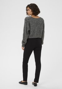 Halli halli kampsun, millel on vabalt langev lõige, ümmargune kaelus, pikad varrukad, kombineeritud kitsaste mustade pükste ja mustade lamedate kingadega, vähese detailitööga.