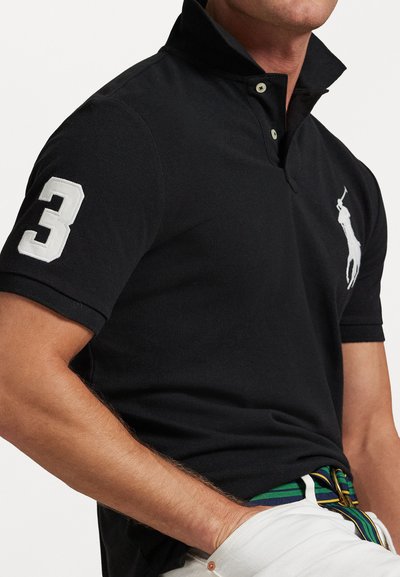 Čierne polo tričko s krátkym rukávom, ktoré má biele vyšívané logo, číslo "3" na rukáve a klasický dizajn goliera.
