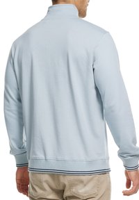 Lyseblå pullover sweatshirt med høj krave, ribbede manchetter og kant, der har mørkeblå striber. Fremstillet af et blødt, tekstureret stof.
