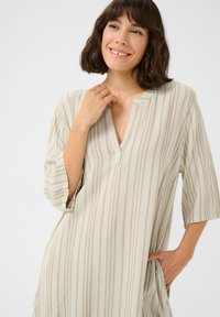 Abito beige con strisce verticali, scollatura a V e maniche a tre quarti. Realizzato in tessuto morbido, con una vestibilità comoda e tasche laterali.
