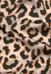 Tkanina s leopardjim vzorom, ki ima svetlo roza ozadje z temno rjavimi in oranžnimi pikami, gladko teksturo in mehak padec.