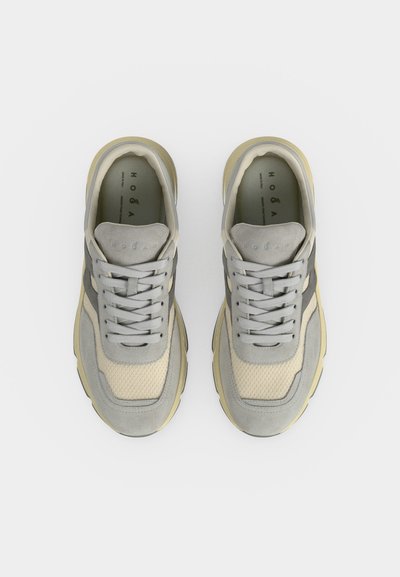 Paire de baskets lacées gris clair et beige vue de dessus sur fond blanc.