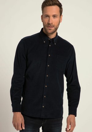 Camicia in corduroy blu navy con colletto a punta, maniche lunghe e taschino sul petto. Presenta bottoni marroni e tessuto texture.