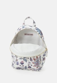 Plecak w biały kwiatowy wzór z fioletowymi i różowymi akcentami. Zapięcie na suwak, mały uchwyt oraz wewnętrzna podszewka w jednolitym białym kolorze.