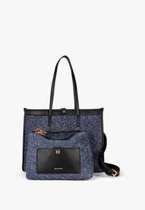 Twee gestapelde tassen: een grotere donkerenblauwe tas van textuurstof met zwart leren details en korte handvatten, en een kleinere bijpassende clutch met gouden hardware.