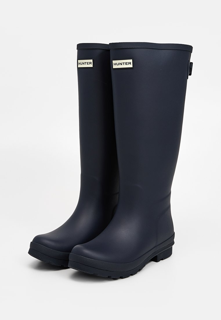 Marineblaue Gummiregenstiefel mit matter Oberfläche, mittlere Schafthöhe und gerillten Akzenten; mit dem "HUNTER"-Logo in der Nähe der Oberseite an beiden Seiten.