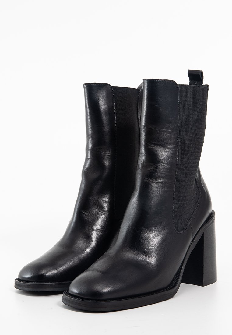 Bottines en cuir noir avec des panneaux latéraux élastiques et un bout carré. Elles présentent une finition texturée et un talon épais et haut pour plus de stabilité.