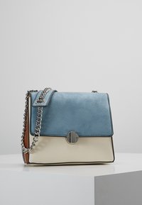 Kabelka z hladké a umělé kůže, s světle modrým vrškem, krémovým tělem a stříbrným řetízkem. Výrazné zapínání na tlačítko na předním klopě.