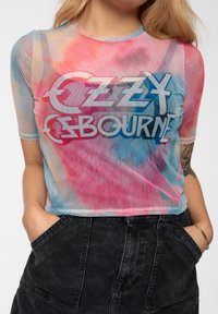 Mesh crop top featuring a tie-dye pattern in pink, blue, and aqua, with a bold white graphic print of "OZZY OSBOURNE" across the chest.