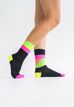 Bunte Knöchelsocken mit schwarzem Grund und neonpink, grün und gelb geometrischen Mustern, strukturiertem Strick und kontrastierenden Zehenakzenten.