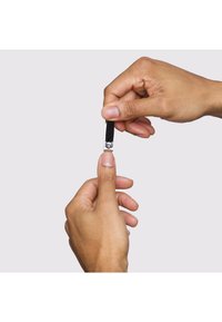 Persona che usa un tagliaunghie per tagliare l'unghia del pollice della mano sinistra, su uno sfondo chiaro e uniforme.