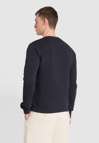 Granatowy sweatshirt z długimi rękawami, okrągłym dekoltem, ściągaczami przy mankietach i dole. Miękka faktura; minimalistyczny design bez widocznych logo i wzorów.