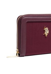 Portafoglio zip-around bordeaux in tessuto con una texture liscia e hardware in tonalità oro, caratterizzato da un logo decorativo.