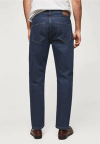 Jeans de mezclilla azul oscuro con corte recto, costuras visibles, dos bolsillos traseros y una parche de cuero marrón en la cintura trasera.