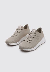 Zapatillas ligeras beige con parte superior de malla texturada, suela de goma blanca y diseño de cordones para un ajuste seguro.
